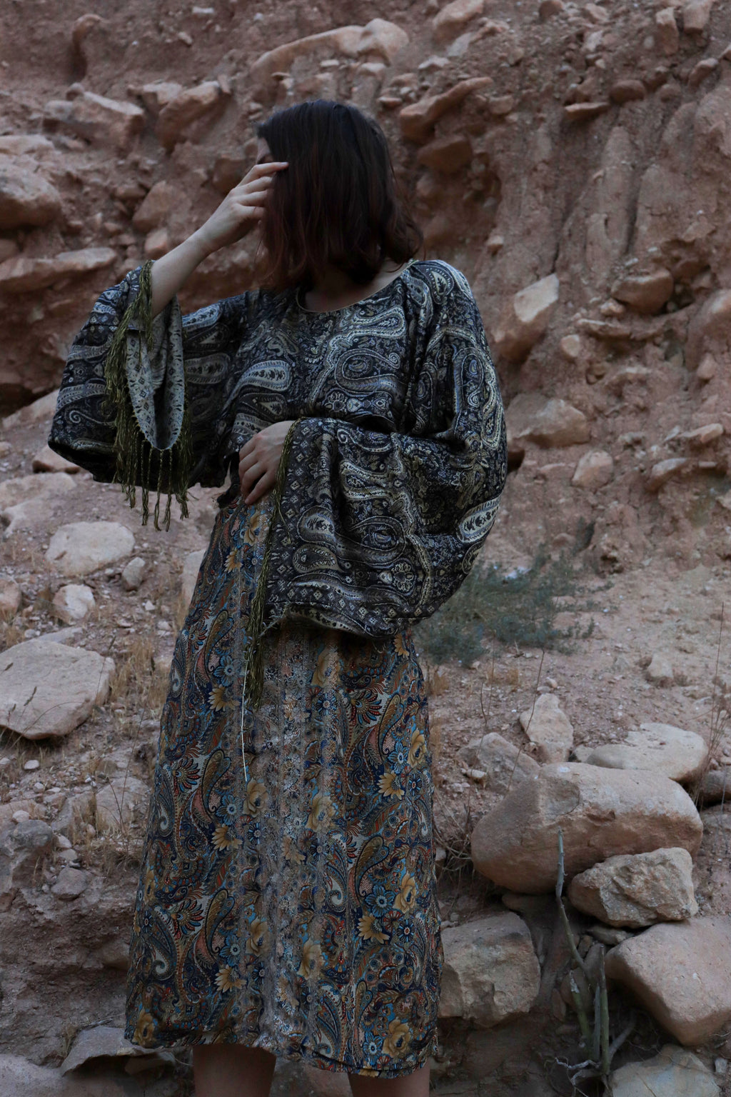 Woman in a patterned dress standing in a rocky desert landscape