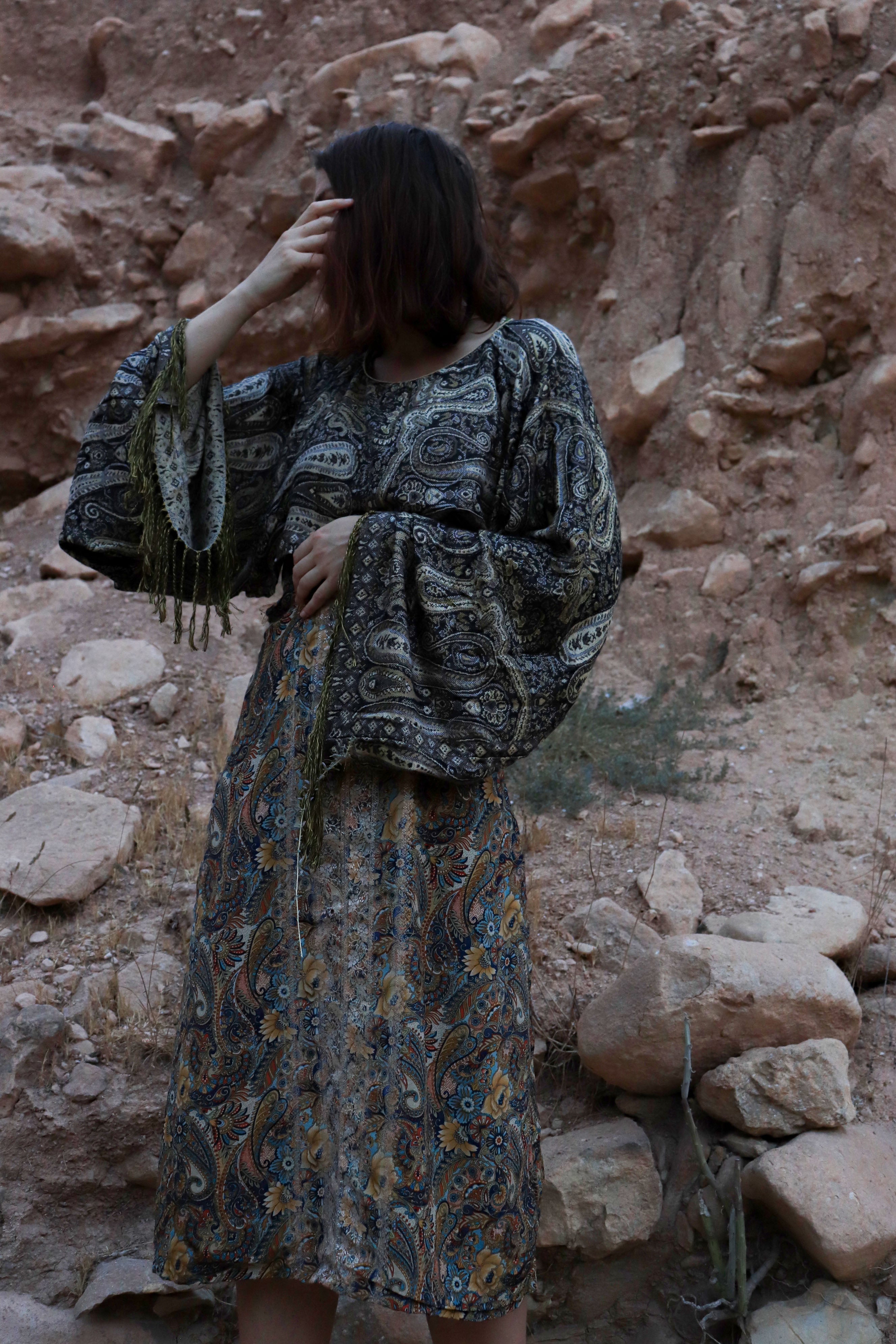 Woman in a patterned dress standing in a rocky desert landscape