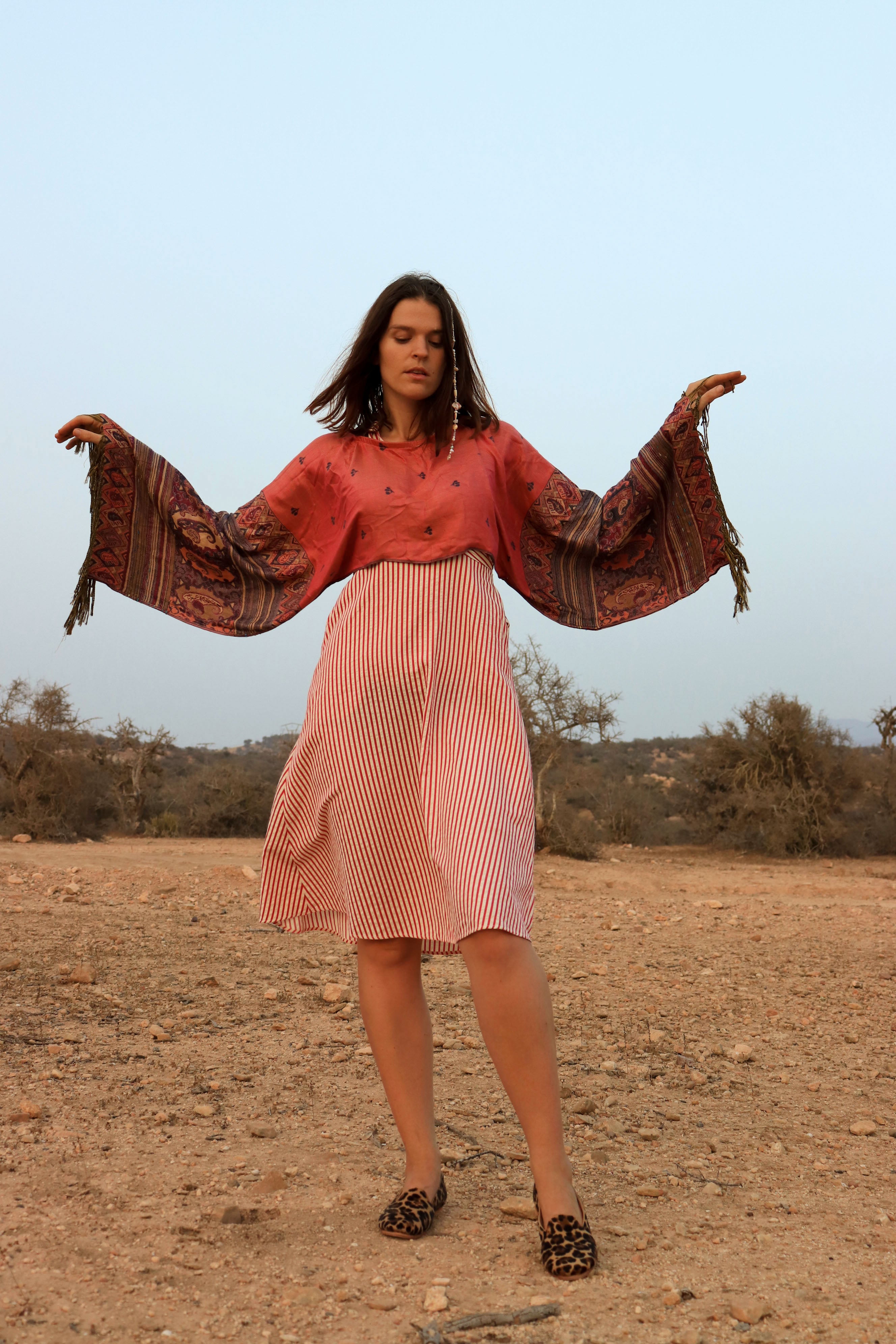 Woman in a pink dress with a patterned shawl in a desert-like setting