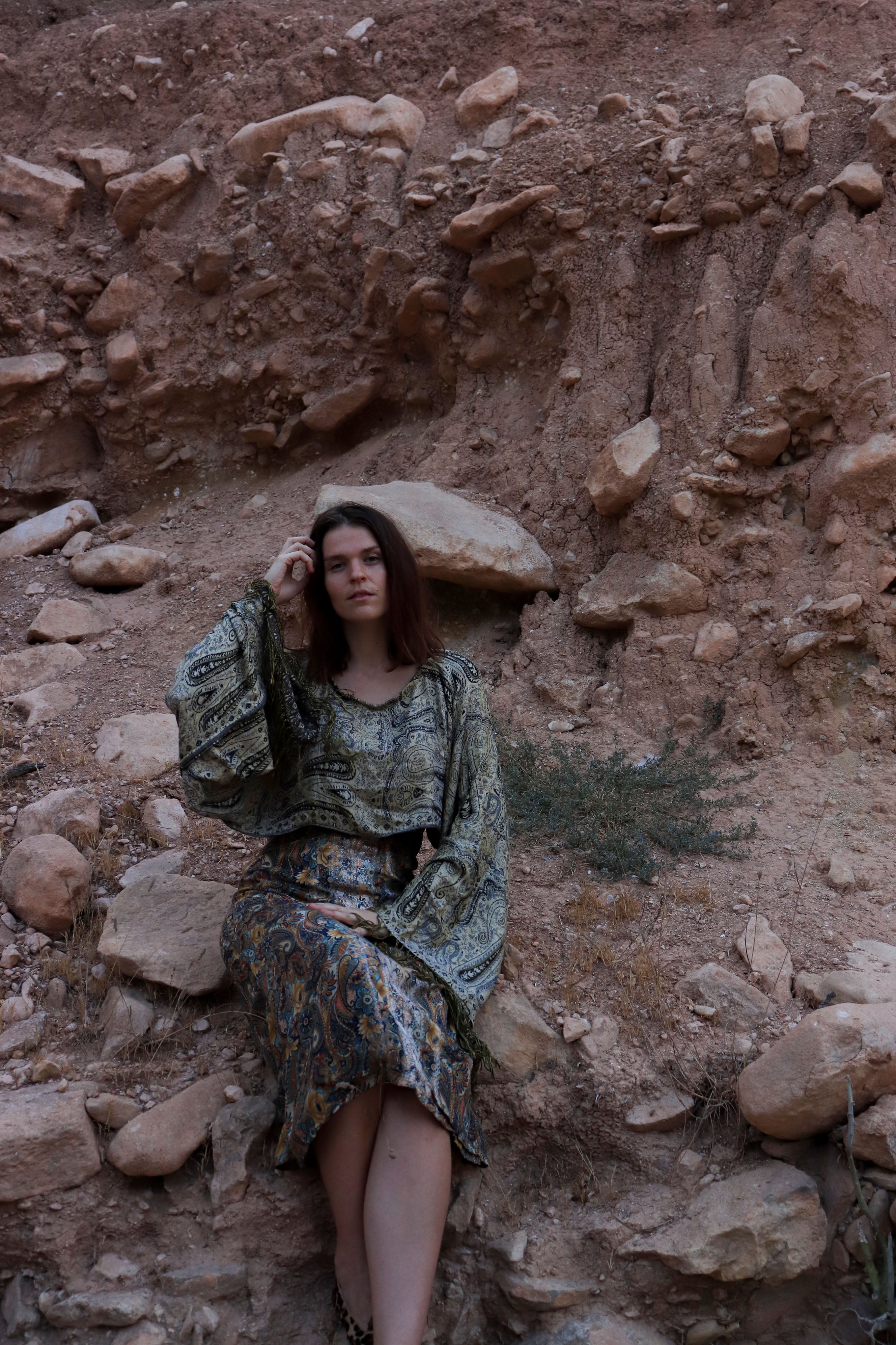 Woman in a patterned dress sitting on rocky terrain
