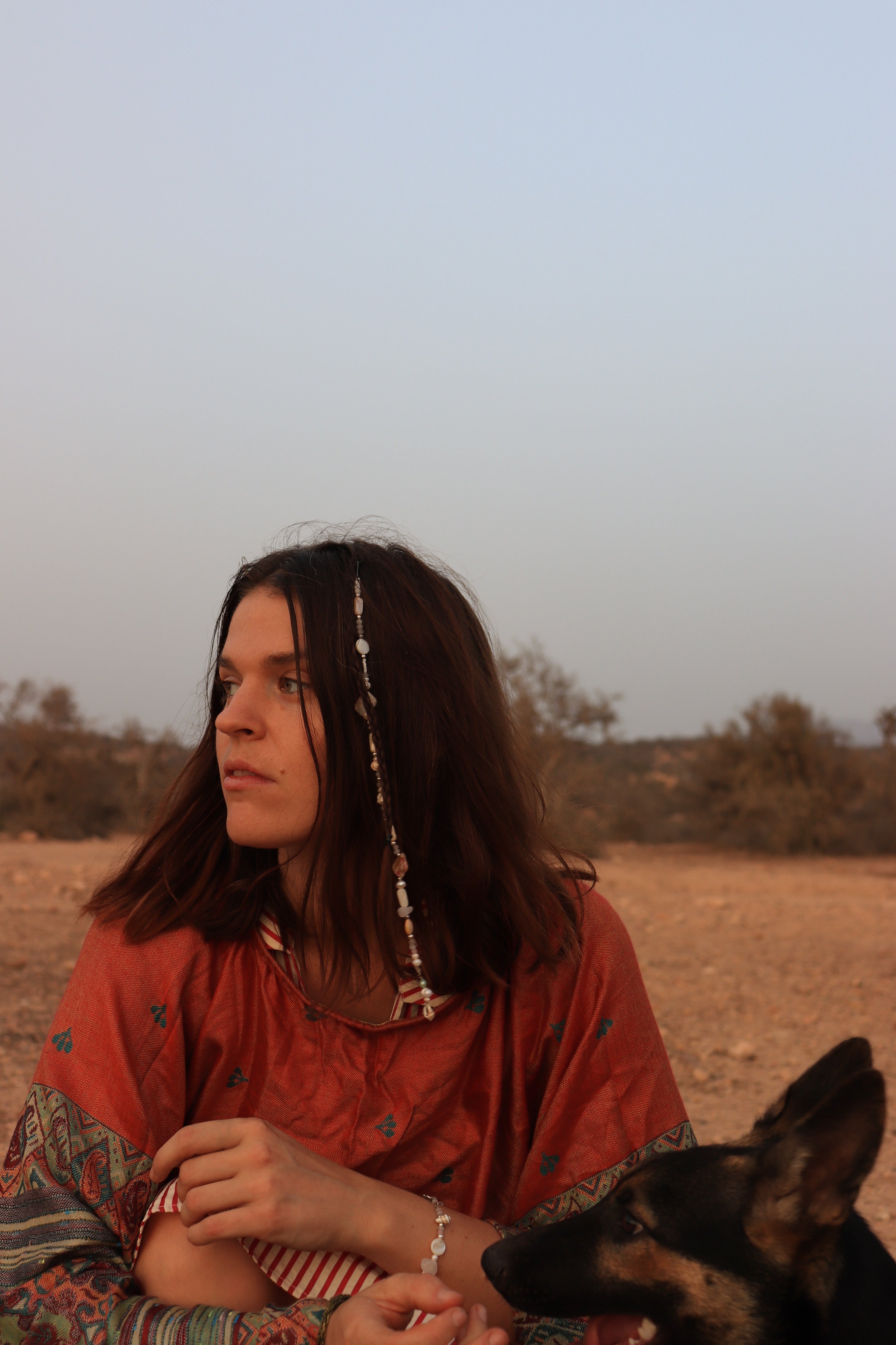Woman in a red shawl sitting outdoors with a dog