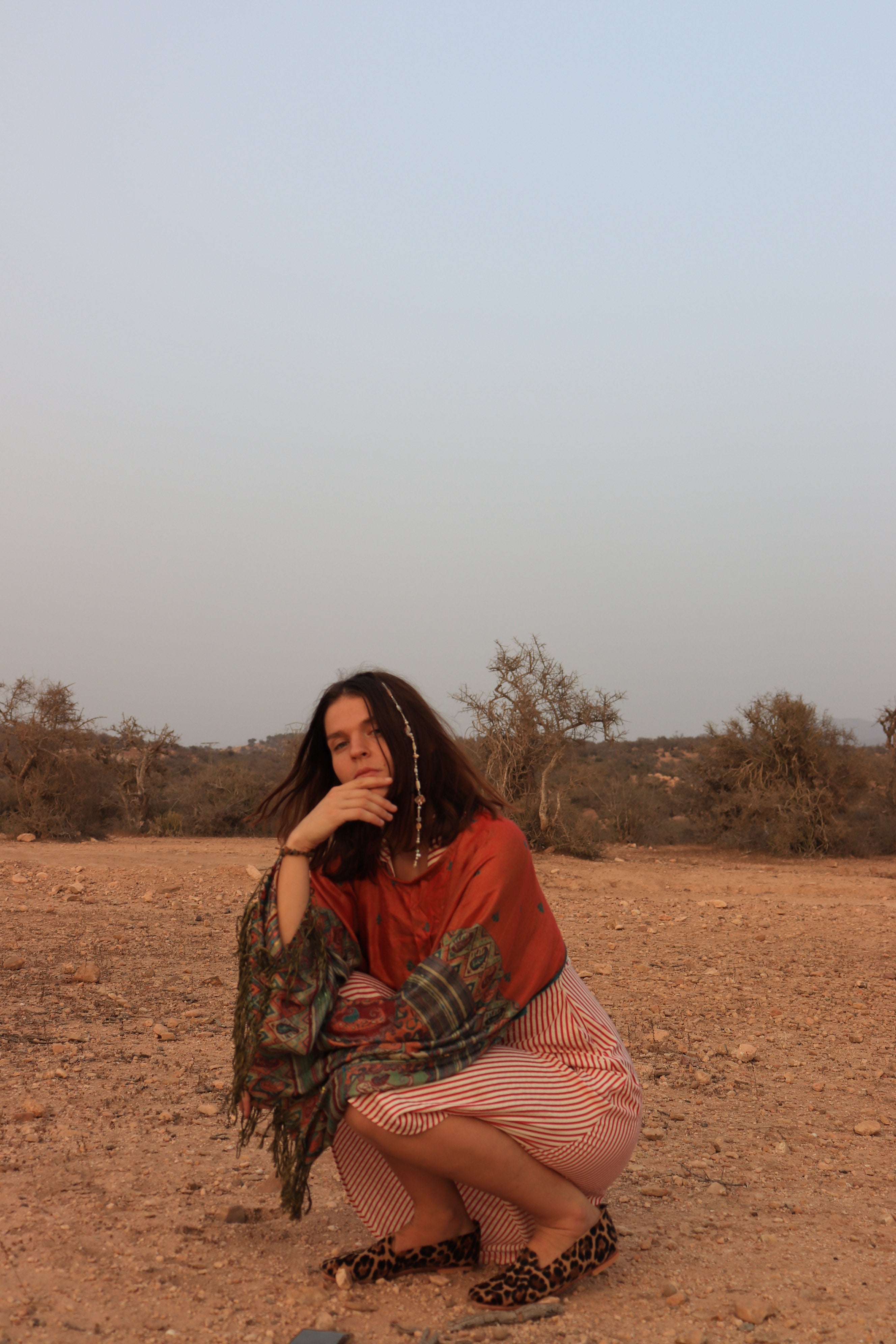 Woman in a desert-like setting with a plain background