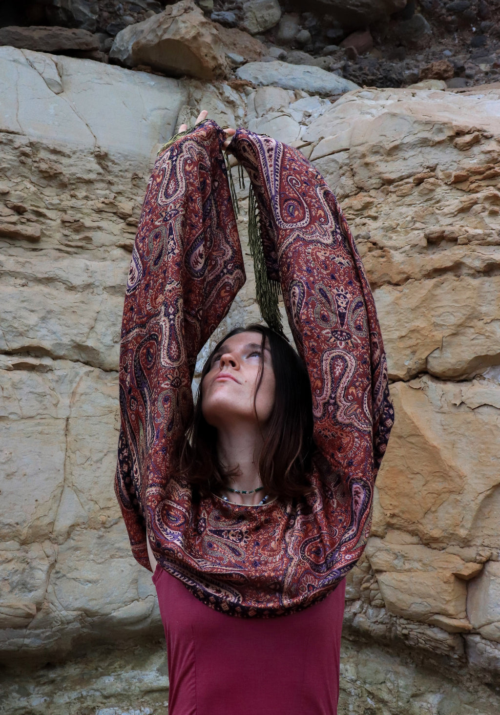 Woman in a patterned dress sitting against a rocky wall