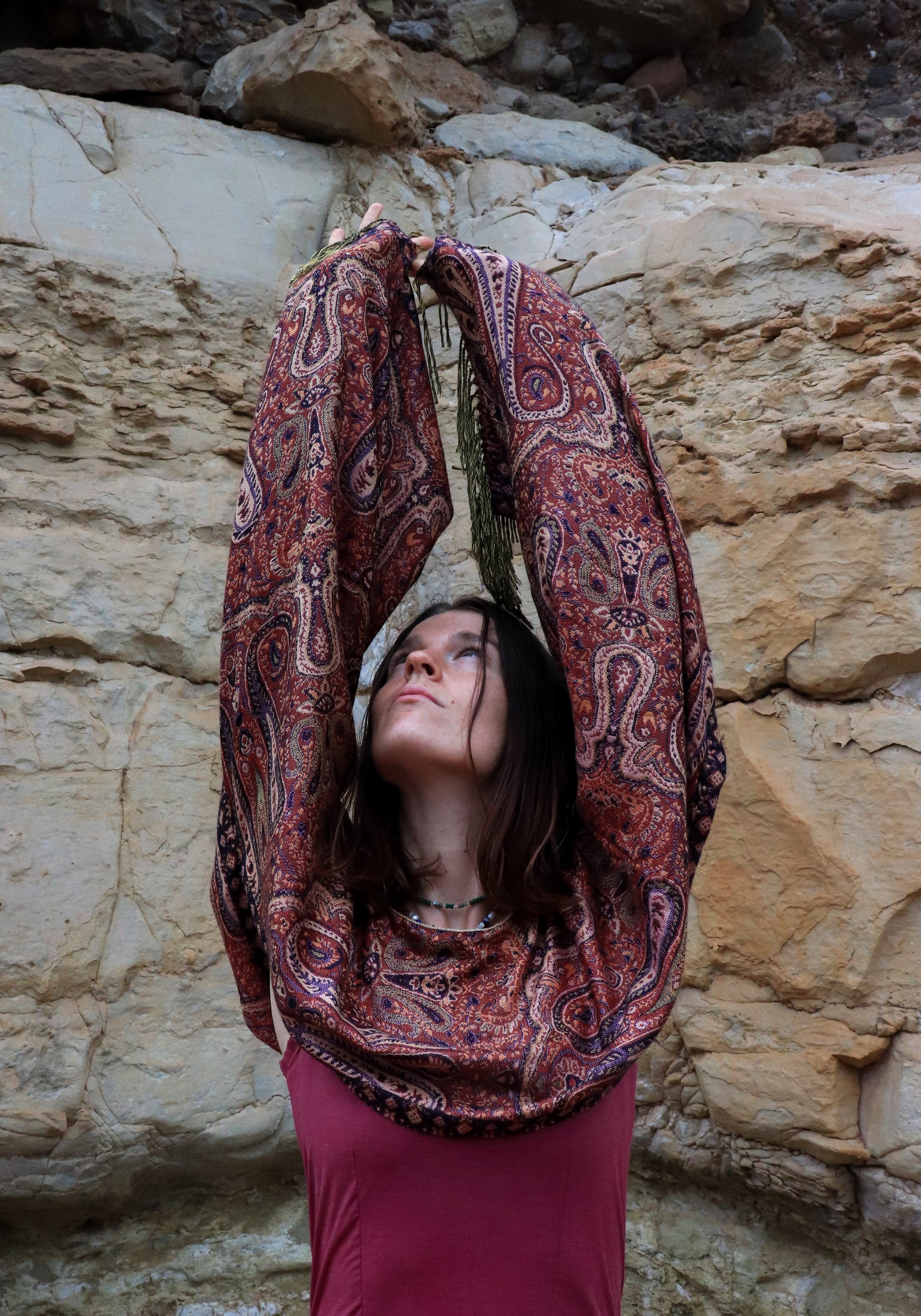 Woman in a patterned dress sitting against a rocky wall
